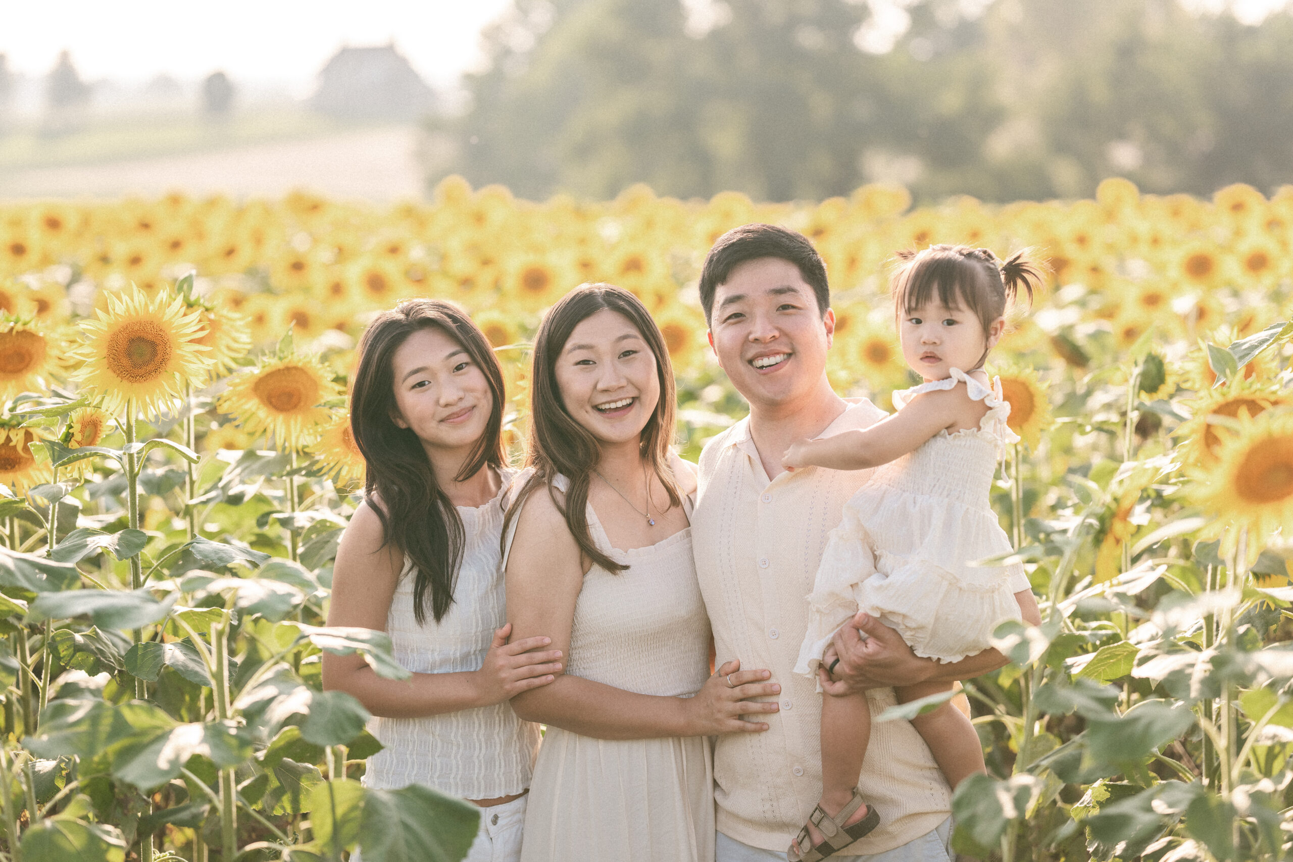 A family of four smiles for the camera in sunflower fields.