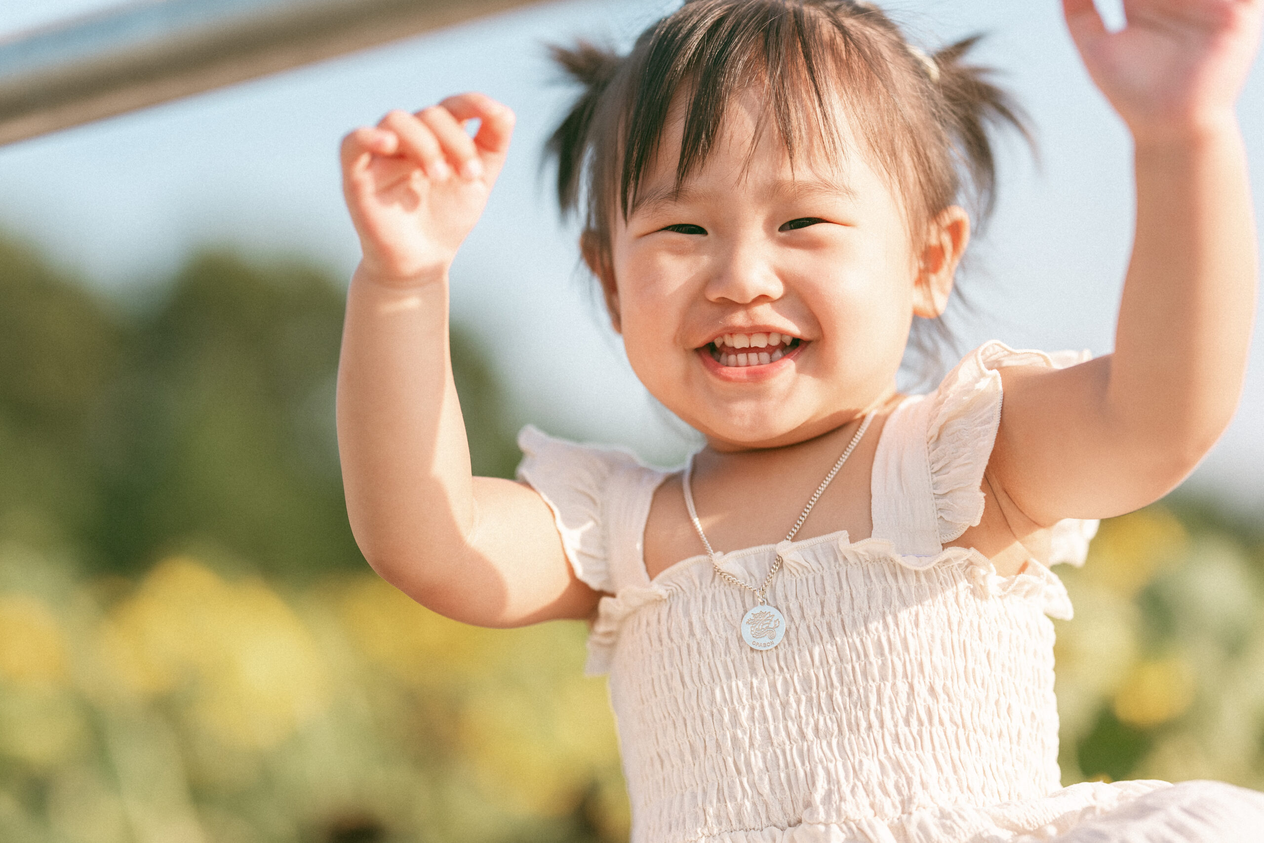 Close-up of a smiling toddler enjoying seasonal family sessions outdoors in the summer sunshine.