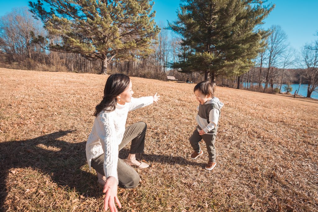 Mom crouching with open arms as her toddler runs toward her during playful Seneca Creek State Park family photos.