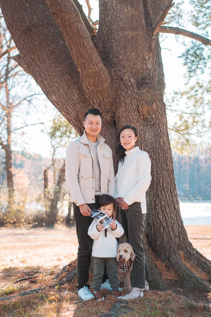 Young boy holding ultrasound photos while his parents stand behind him with their family dog.